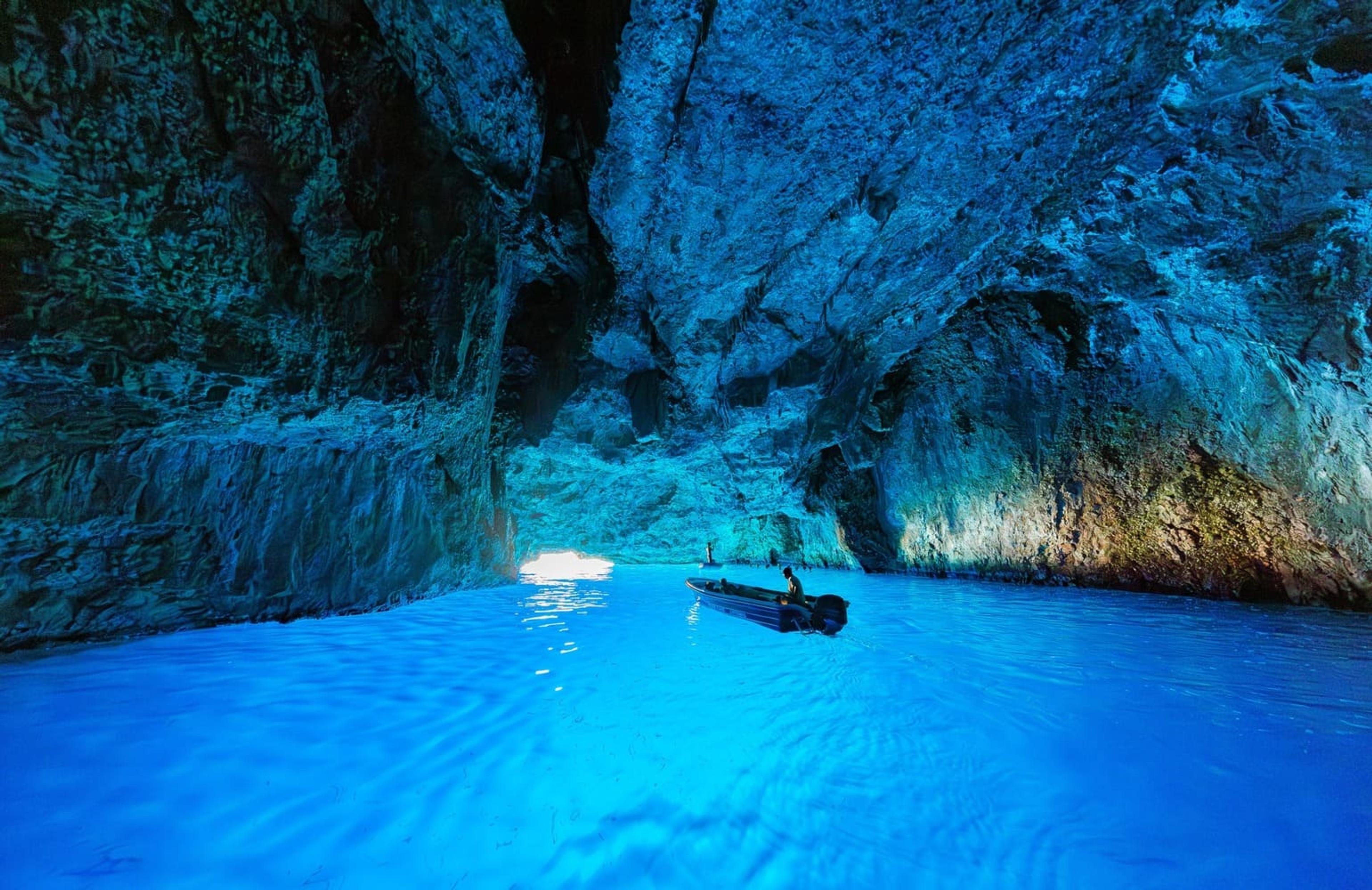 A boat inside the vivid blue water of the Blue Cave near Meis