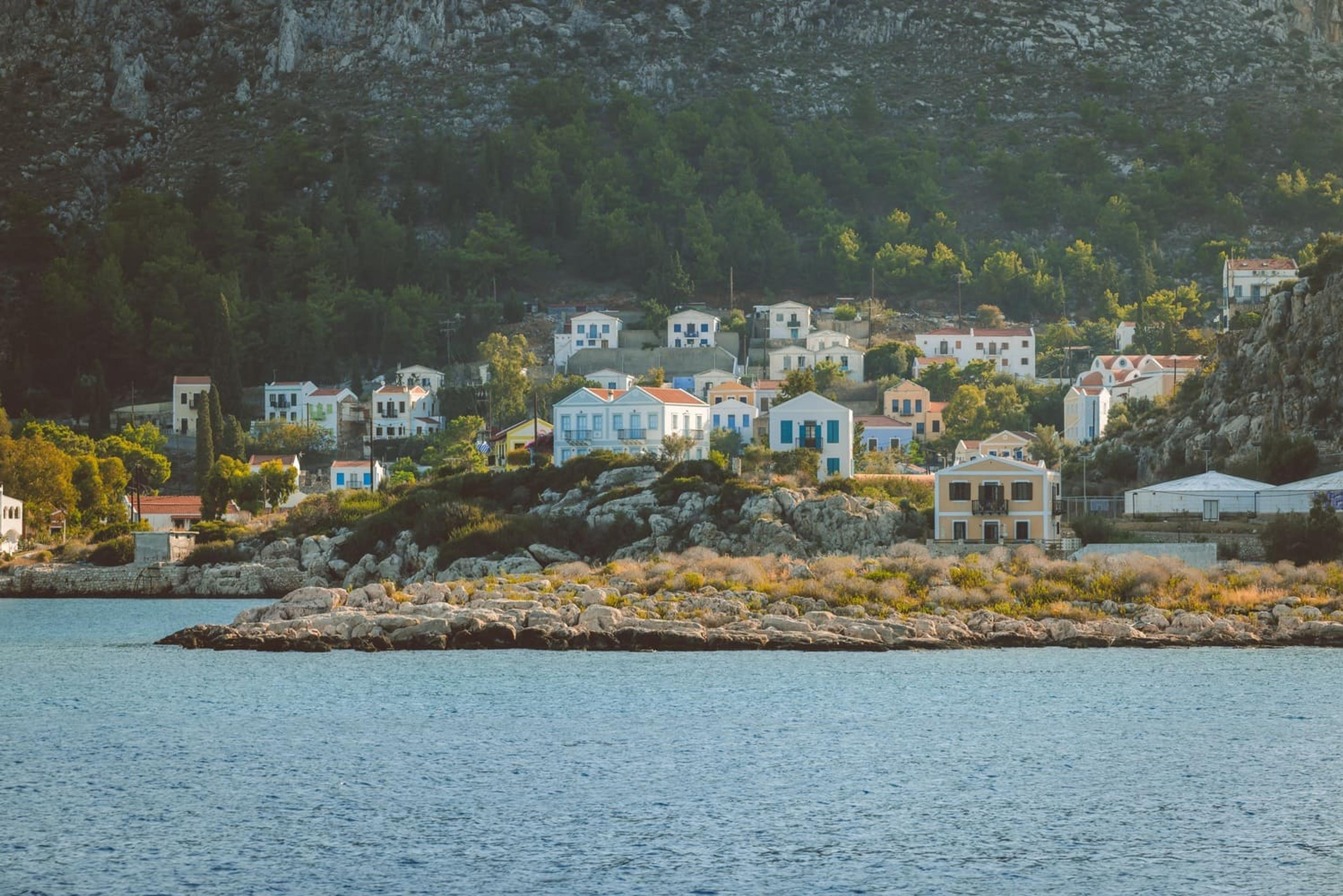 Approaching Meis by sea, houses clustered on the rocky shore